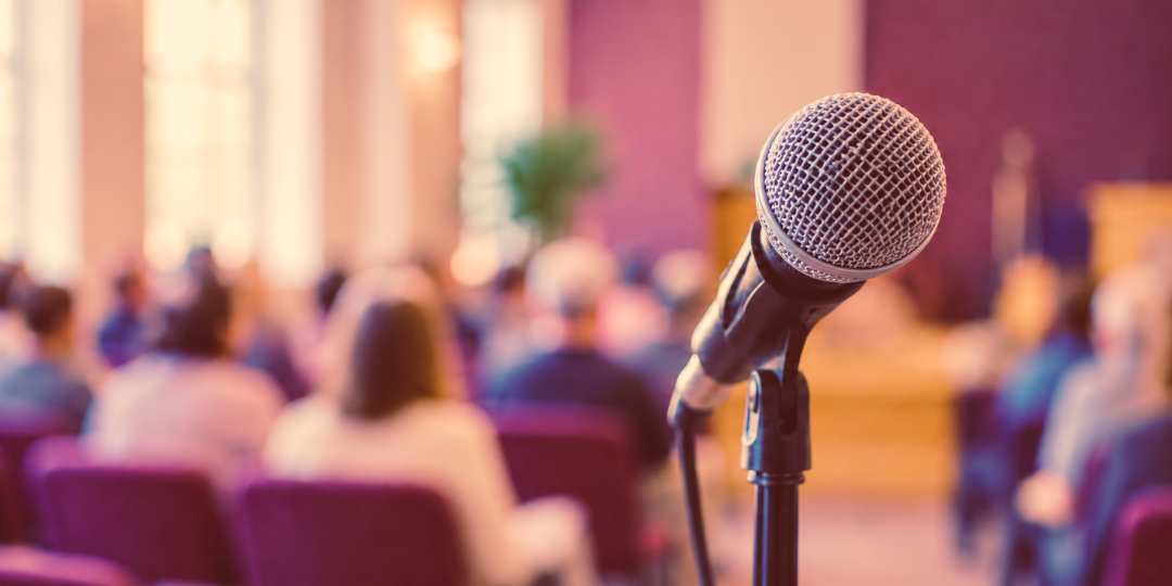 A microphone on a stand in front of a church congregation